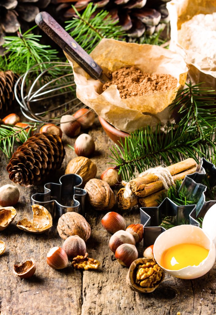 Christmas or New Year baking cake background. Dough, dough ingredients - flour, chocolate, walnuts, hazelnuts, sugar eggs cinnamon and Christmas decorations on wooden rustic background